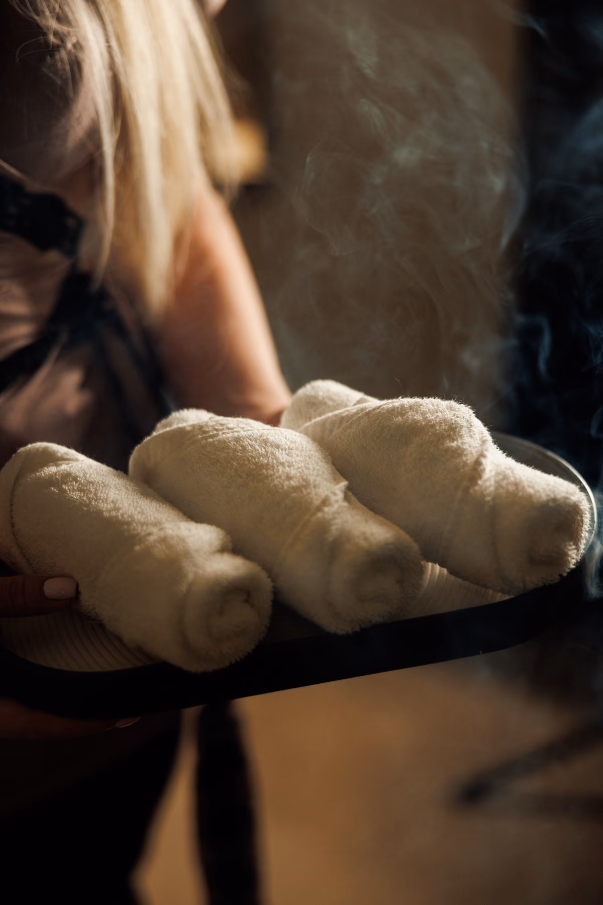 Therapist carrying a tray of hot rolled towels in steam, part of the Royal Hammam ritual at Lavana Spa